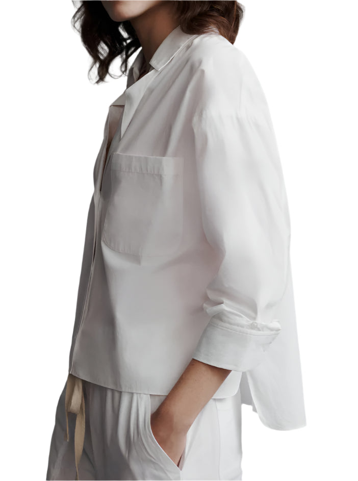 Person wearing a relaxed fit, loose-fitting white cotton TWP Day After Top and matching pants, with hands in pockets, on a white background.