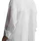 Against a plain background, a person is seen from behind wearing the TWP Day After Top, a relaxed fit cotton poplin shirt, paired with white pants, exuding effortless style.
