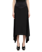 A person wearing a Stella McCartney Silk Midi Skirt with a fitted waistband and high-low hem, paired with black patent shoes.