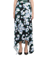 A person wearing the Stella McCartney Bunch of Roses Skirt with a black base, white and blue floral print, asymmetrical hemline, paired with black pointed-toe shoes.