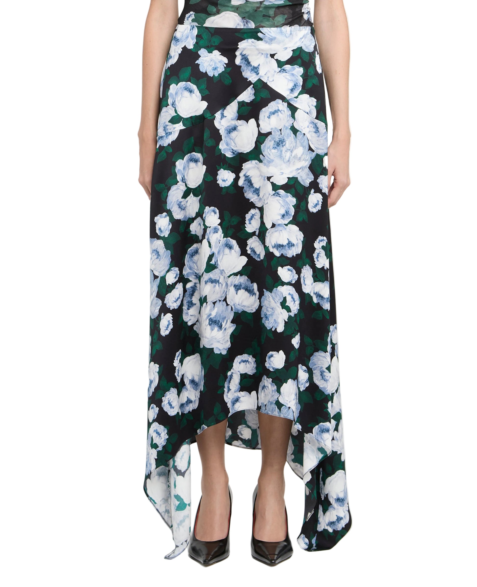 A person wearing the Stella McCartney Bunch of Roses Skirt with a black base, white and blue floral print, asymmetrical hemline, paired with black pointed-toe shoes.