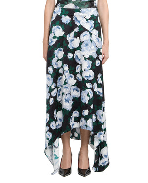 A person wearing the Stella McCartney Bunch of Roses Skirt with a black base, white and blue floral print, asymmetrical hemline, paired with black pointed-toe shoes.