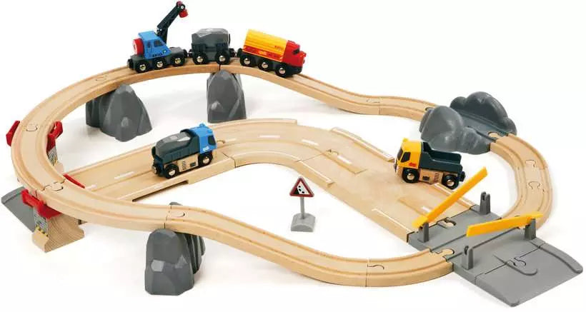 A BRIO World Rail & Road Loading Set with interconnected tracks, bridges with railway track supporters, a crane, a traffic sign, and several vehicles including a fire engine, a train, a truck, and a crossing gate offers an immersive Brio experience.