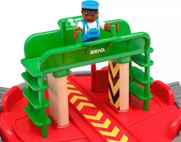 The BRIO World Turntable & Figure features a green platform with a small figure on top. Its red base includes elements from the BRIO World railway, such as track splits, wooden pillars, and smooth track connections for imaginative and versatile play.