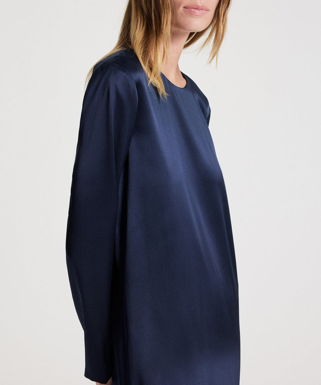 A person wearing a long-sleeved, navy blue, round-neck TWP Nightfall Dress.