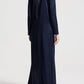 Back view of the TWP Nightfall Dress, a floor-length, long-sleeved navy gown featuring a neckline slit and a slight train.