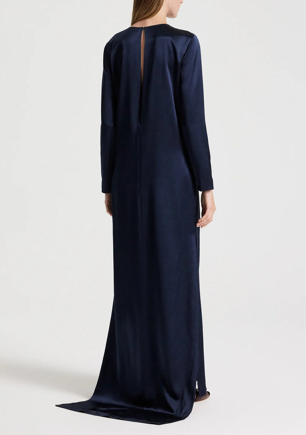 Back view of the TWP Nightfall Dress, a floor-length, long-sleeved navy gown featuring a neckline slit and a slight train.