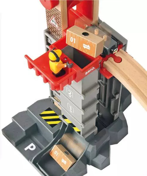 The BRIO Lift & Load Warehouse Set by Brio includes a worker figure in an orange outfit standing on a red platform, surrounded by tracks, blocks, and stackable bridges. Ideal for imaginative play, this railway set enables young builders to explore endless possibilities with its multi-storey lift design.