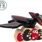 A magnet shaped like a black and red bird rests on a wooden block adorned with abstract designs, evoking the prehistoric themes of Brio's BRIO World Dinosaur Erupting Volcano.