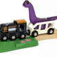 The BRIO Dinosaur Adventure Set by Brio features a toy train with an engine and carriage holding a purple dinosaur, running on a wooden track adorned with flower decorations on the green platform area.