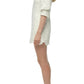 Woman in the Simkhai Freya Linen Dress, an ivory embroidered mini with three-quarter sleeves, paired with white heeled sandals, standing in profile against a plain white background.