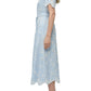 Woman in profile wears the Simkhai Audria Belted Midi Dress in light blue lace with scalloped edges, paired with white heeled sandals.