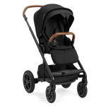 The Nuna MIXX Next Stroller in black, showcasing stylish brown handles and large wheels, is pictured from a three-quarter angle. Its compact folding design and MagneTech Secure Snap™ provide both elegance and practicality for every trip.