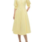 A woman wears the Simkhai Jazz Pintuck Midi Dress in light yellow cotton, featuring a collared neckline, A-line silhouette, button-down front, elbow-length sleeves, and pockets, paired with white heeled sandals.