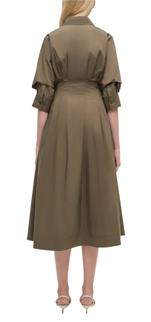A woman stands facing away, wearing the Simkhai Signature Jazz Dress with elbow-length sleeves and silver sandals against a plain white background.