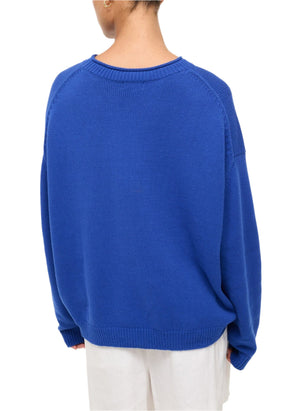 A person faces away, wearing the lightweight Staud Giada Sweater with blue and white shorts against a plain background.