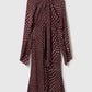 The Stella McCartney Tie-Neck Polka Dot Silk Dress, featuring long sleeves, a knee-length midi silhouette, and a flattering maroon polka dot design with flared cuffs and a chic tie-neck detail, is displayed against a light background.