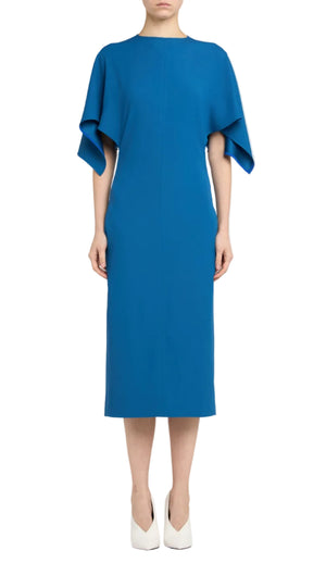 A woman models the Stella McCartney Royal Blue Midi Dress, featuring wide draped short sleeves, paired with white closed-toe heels against a white background.