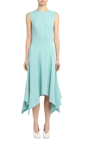 A person wearing the Stella McCartney Aquamarine Midi Dress with a handkerchief hem and white shoes, standing against a plain background.