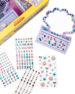 The Super Smalls Mini Mermaid Vanity Gemify Kit includes a plastic shell mirror, gem stickers, pearl accents, and decorative sheets with colorful jewels and sea-themed designs.