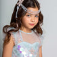A young girl with long brown hair wears the Tutu du Monde Girls’ Mermaid Magic Tutu Dress, featuring sparkling sequins and a beaded headpiece, as she gazes at the camera against a simple light background, capturing the enchanting essence of a mermaid costume.