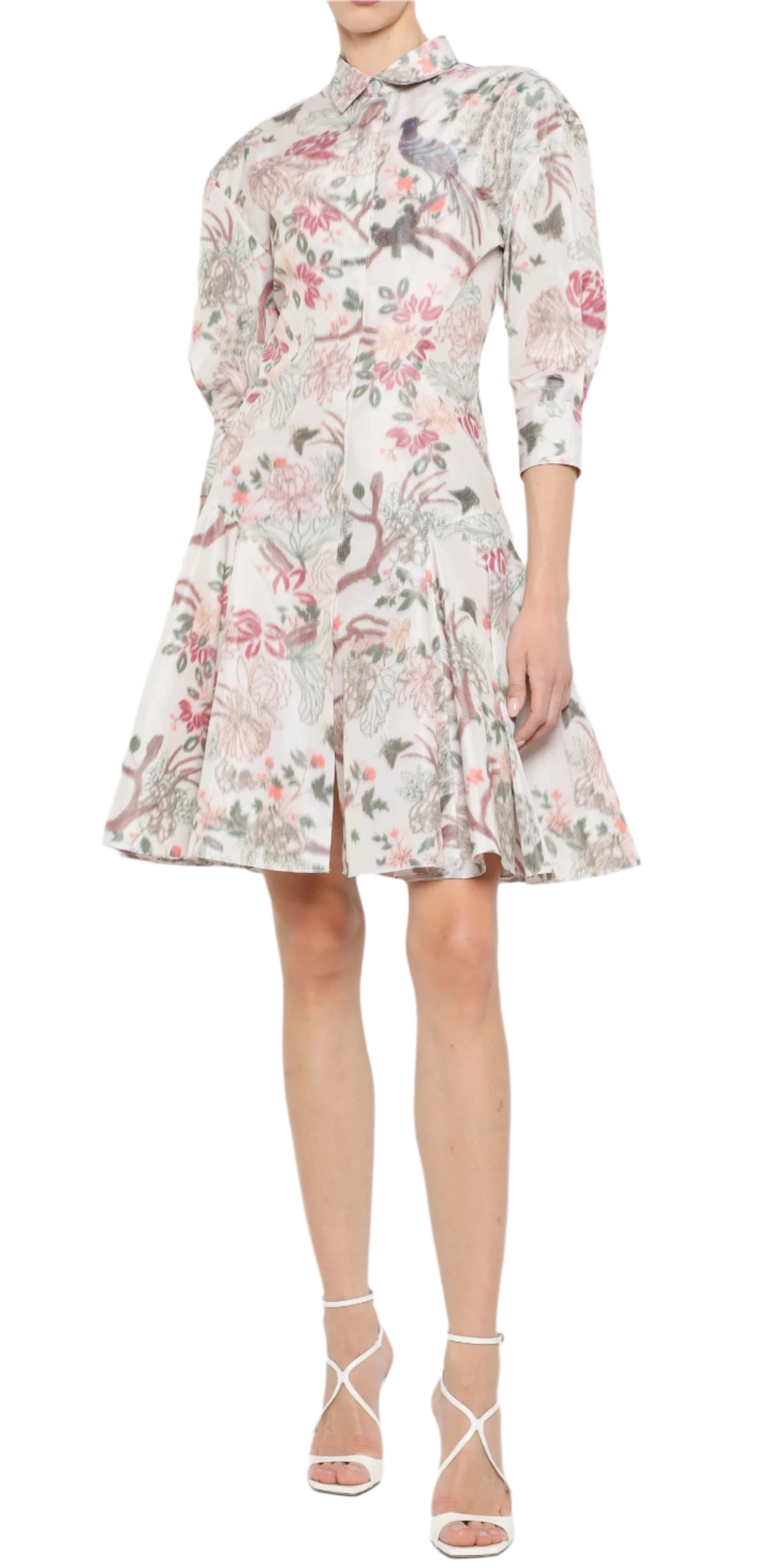 Wearing a Prabal Gurung Mini Shirtdress with floral patterns and three-quarter sleeves, paired with white strappy heels, this person standing against a plain background embodies effortless style and comfort.