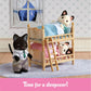 Two Calico Critters figures are cozily tucked into the Stack and Play Beds, each with a soft blanket, while a third cat in a shirt and tie stands close by. A window reveals the night sky, completing this charming dollhouse furniture scene from Calico Critters. The text below reads: “Time for a sleepover!”.