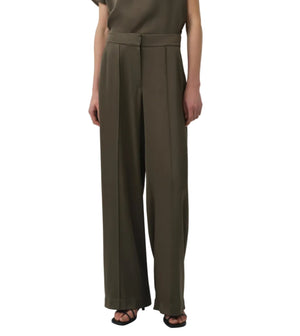 Wearing the Simkhai Kyra Wide Leg Pant in olive green with a tailored waistband and pleats, styled with a matching top and black open-toe heels for a polished yet relaxed look.