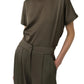 Wearing the Simkhai Kyra Wide Leg Pant with a tailored waistband, paired with an olive green short-sleeve top for a relaxed look—hands in pockets.