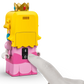 A finger presses the power button on a LEGO® Peach™ figure with yellow hair, a crown, and pink dress from the Legos - Toyhouse LEGO® Super Mario™ Adventures with Interactive LEGO® Peach™, set against a white background.
