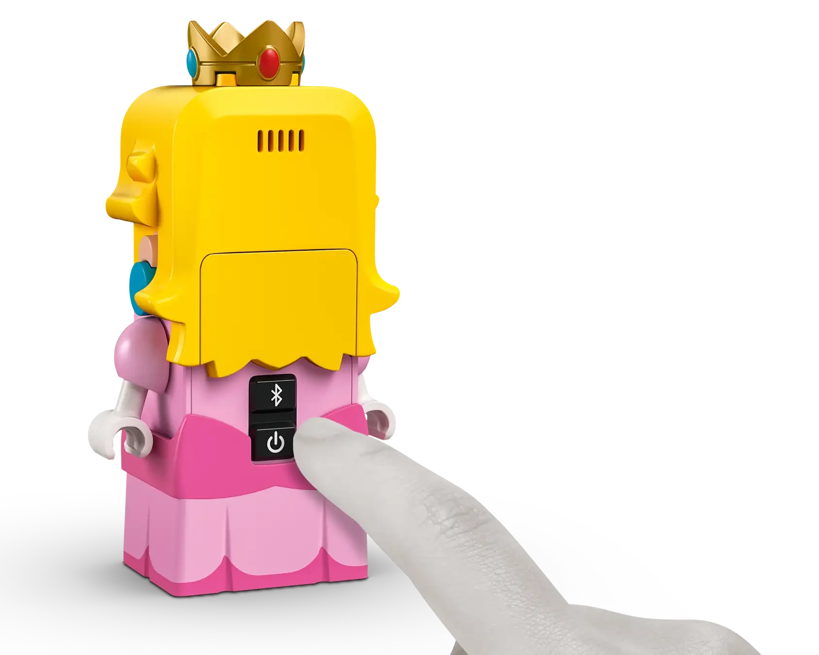 A finger presses the power button on a LEGO® Peach™ figure with yellow hair, a crown, and pink dress from the Legos - Toyhouse LEGO® Super Mario™ Adventures with Interactive LEGO® Peach™, set against a white background.