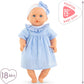 The Corolle Premier Calin - Milly Doll is a 12-inch soft-bodied baby doll with blue eyes, dressed in a blue and white gingham outfit and matching headband—ideal as a first doll for children 18 months and older.