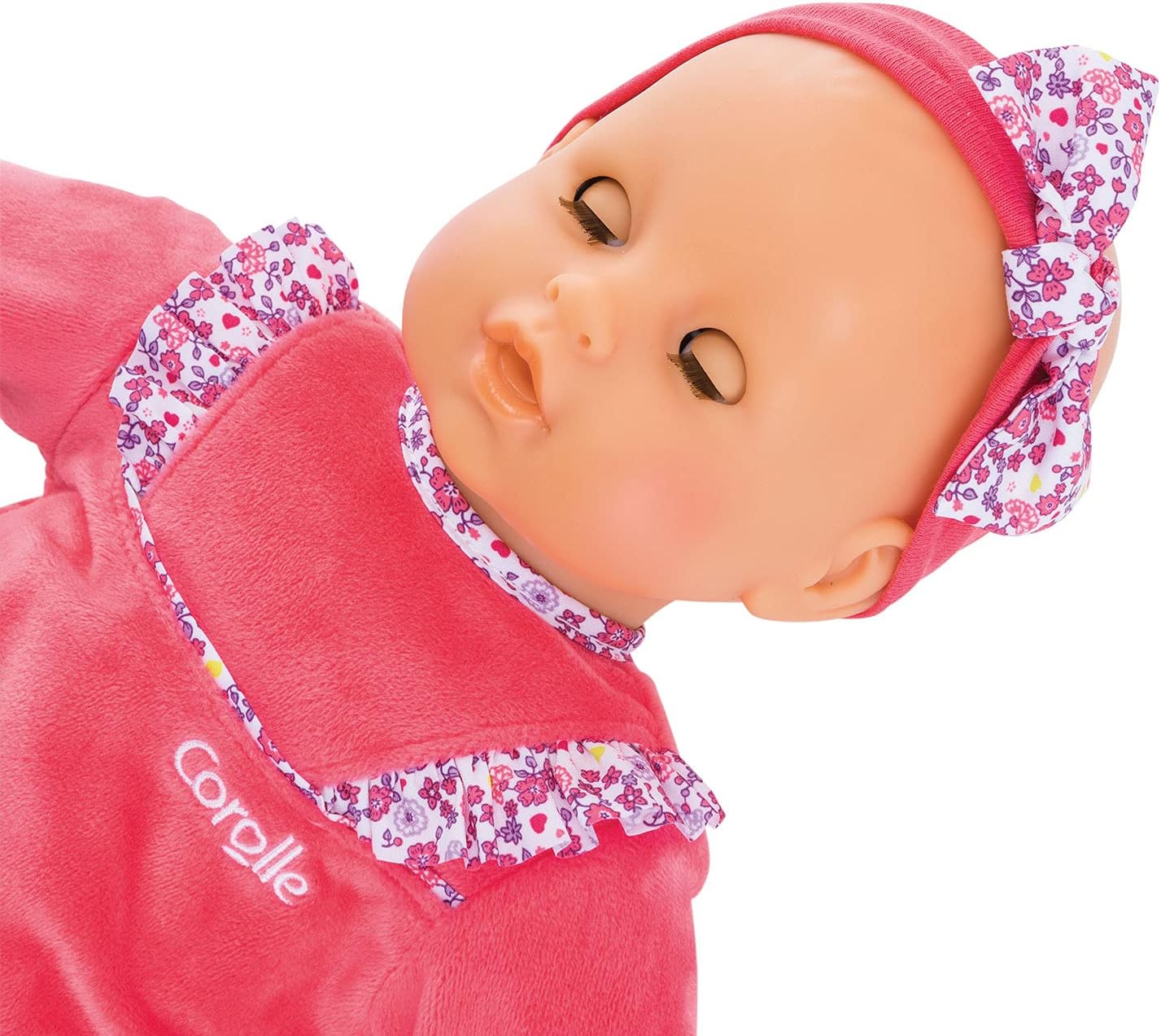 The Corolle Lila Chérie 17" doll is made of soft-touch vinyl, features closed eyes, and wears a pink floral headband with a matching pink outfit branded "Corolle" on the chest.