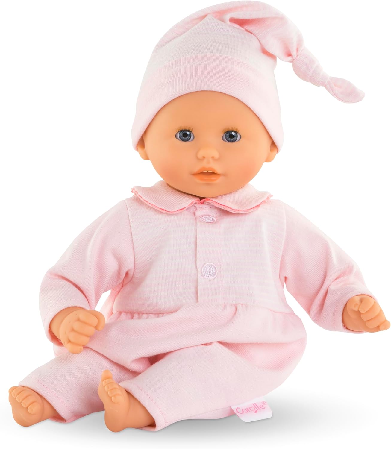 The Corolle Bebe Calin - Charming Pastel 12" baby doll features blue eyes, a pink outfit with matching hat, and a soft body—ideal as a first doll for little ones.