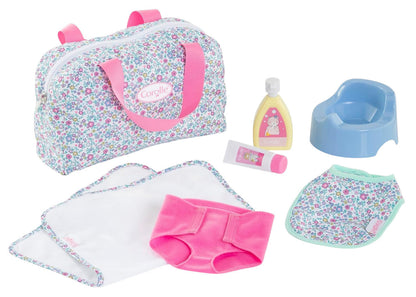 The Corolle Floral Changing Accessories Set includes a potty, lotion bottle, cream tube, 2 cloths, bib, and pink underwear.
