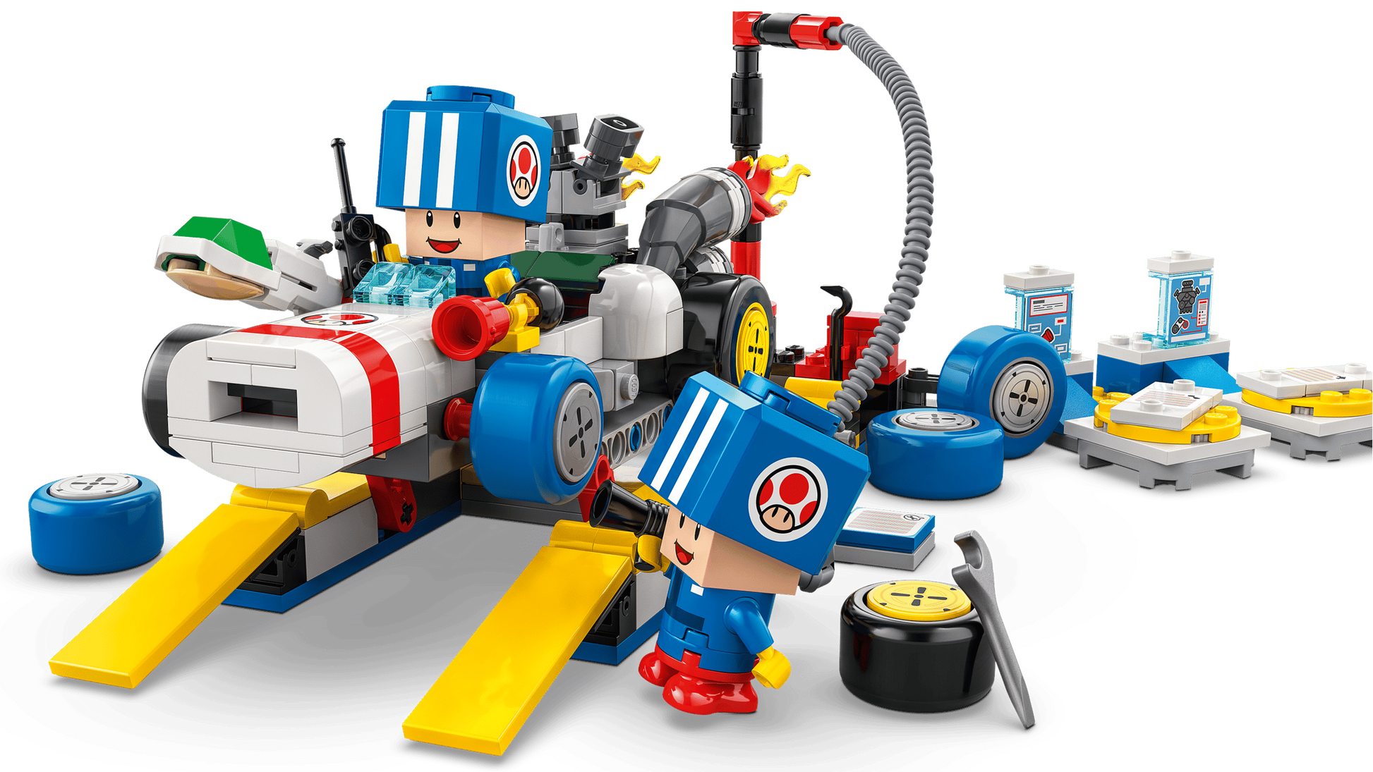 Two LEGO figures in blue helmets work on the LEGO® Super Mario™ Mario Kart™ – Toad's Garage by Legos - Toyhouse, with car parts, tools, and accessories scattered around them on a white background.