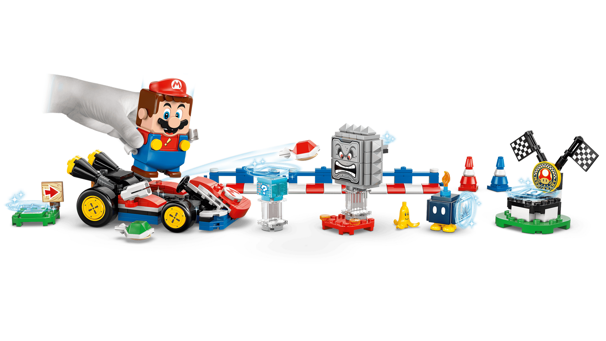 A hand places a LEGO® Mario™ figure into the LEGO® Super Mario™ Mario Kart™ – Interactive LEGO® Mario™ & Standard Kart by Legos - Toyhouse, surrounded by racing obstacles like a Thwomp, road signs, cones, and a finish line.