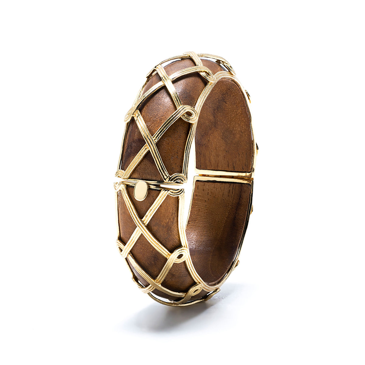 The Earth Goddess Hinged Bangle by Juliska Capucine De Wulf is a hand-carved teak wood bracelet with an openable clasp, adorned with an elegant golden lattice design on the exterior.
