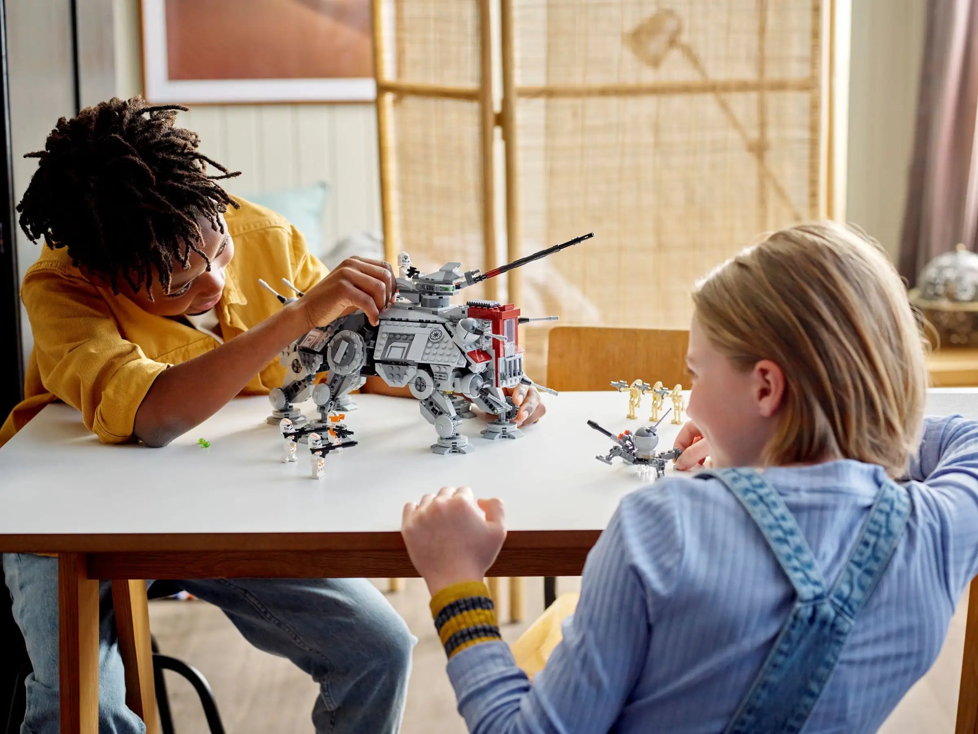 Two children are deeply engrossed in assembling their LEGO® Star Wars AT-TE Walker, carefully constructing each intricate piece from the set by Legos - Toyhouse, as scenes from Star Wars: Revenge of the Sith come to life in their imagination.