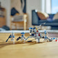 Four minifigures from the LEGO® Star Wars™ 501st Clone Troopers™ Battle Pack by Legos - Toyhouse, each with weapons and an AV-7 anti-vehicle cannon, are displayed on a wooden floor in a bright room.