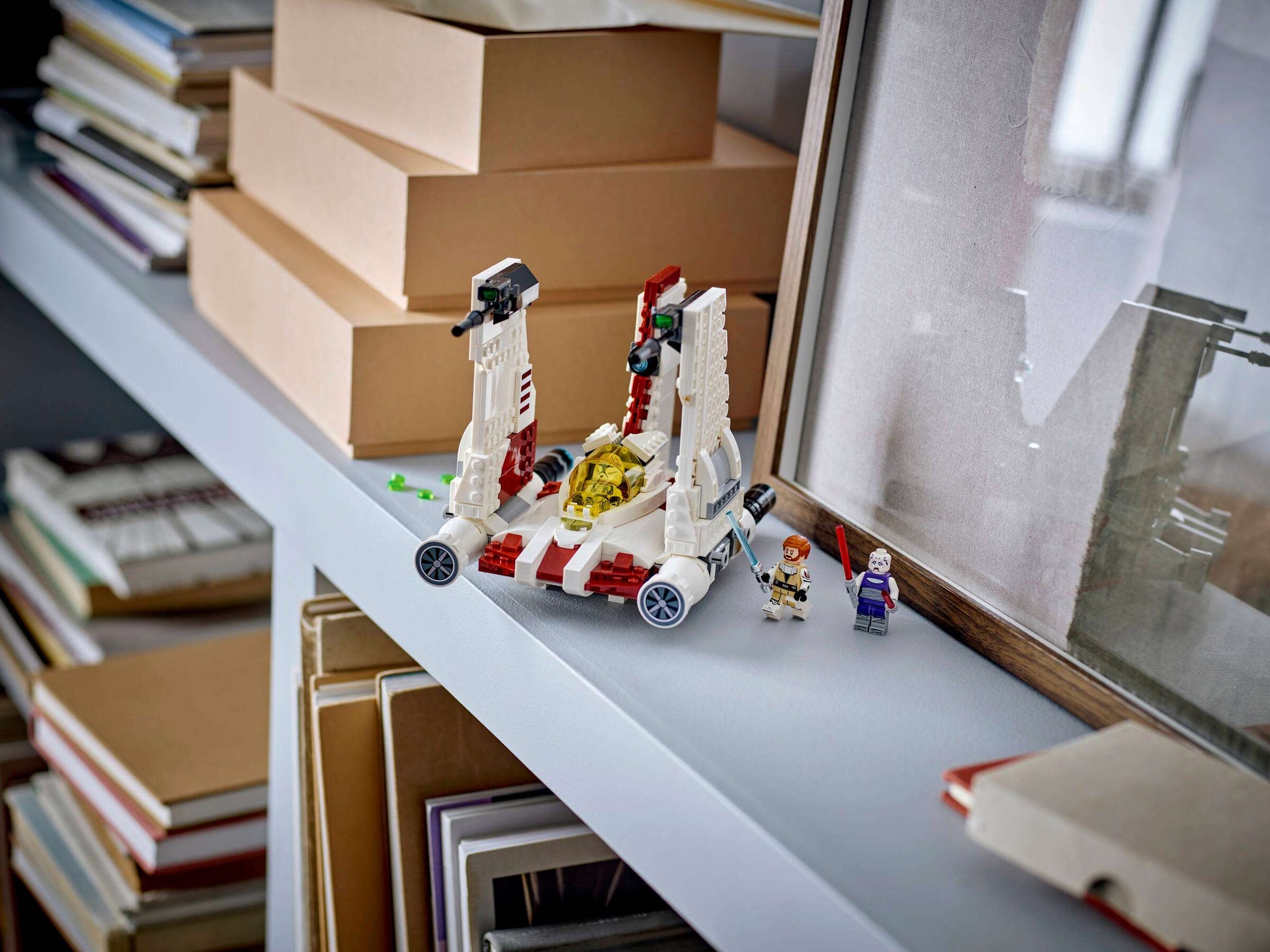 The LEGO® Star Wars™ V-19 Torrent Starfighter from Legos - Toyhouse, with two minifigures, is displayed on a shelf among books and boxes—an ideal building toy for both kids and collectors.