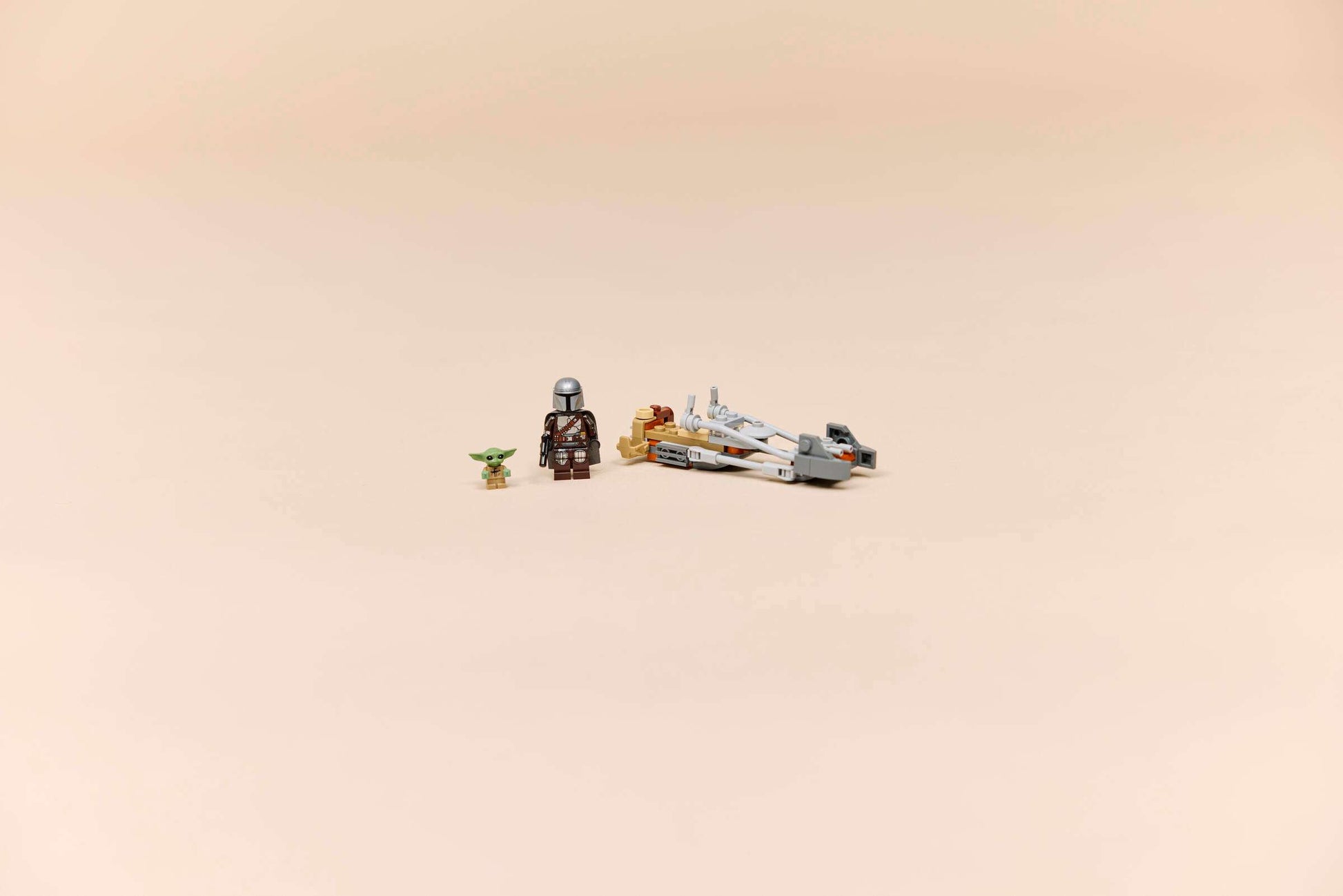 The LEGO® Star Wars™ The Mandalorian & Grogu's Speeder Bike™ by Legos - Toyhouse features Mandalorian and Grogu minifigures beside a small speeder bike building toy for kids on a plain beige background.