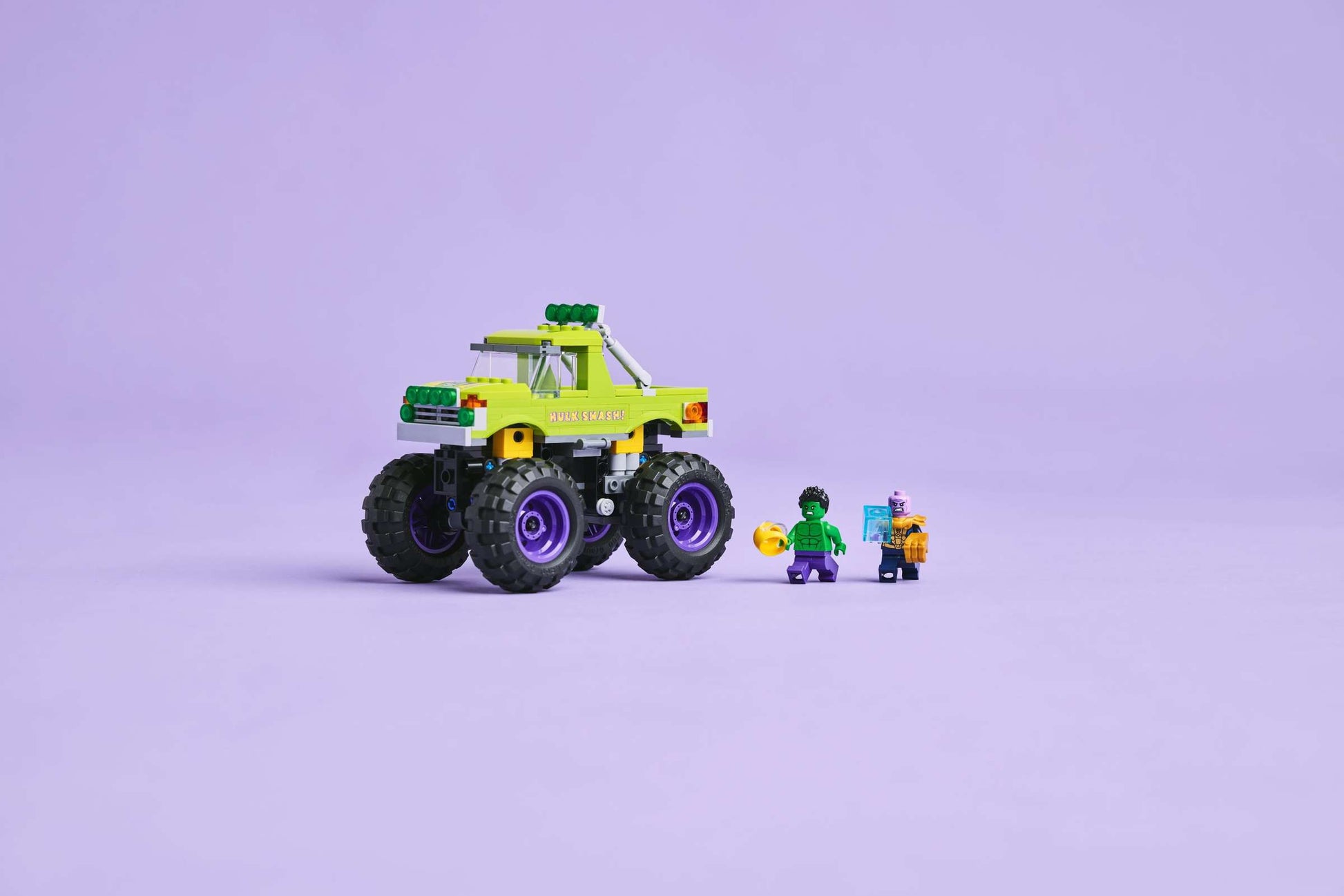 The LEGO® Marvel The Hulk Truck vs. Thanos set by Legos - Toyhouse, featuring a lime green Hulk Truck and three minifigures including Thanos, is displayed on a light purple background.