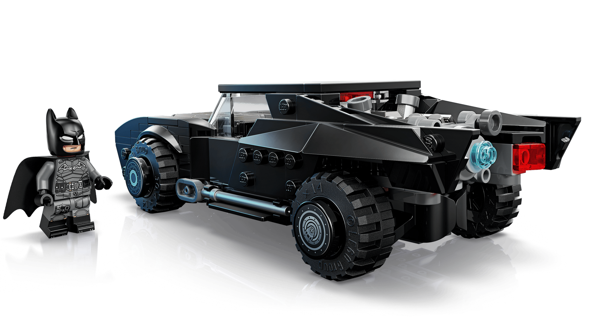 A LEGO® Batman™ minifigure stands by the LEGO® Batman™ The Batman™ Batmobile™, a Legos - Toyhouse model featuring large wheels and a detailed rear jet exhaust.