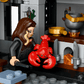 A LEGO® Harry Potter™ Malfoy Manor figure with long brown hair holds a red lobster in a detailed kitchen scene with fireplace, utensils, and gold cup—an enchanting Legos - Toyhouse gift for fans.