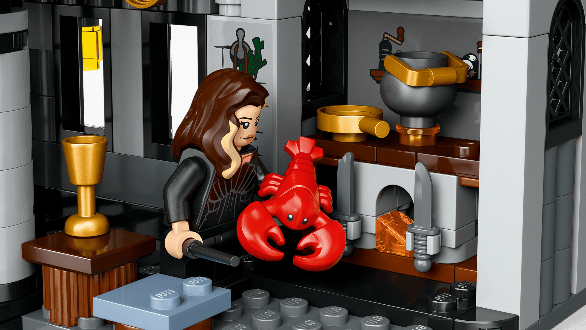A LEGO® Harry Potter™ Malfoy Manor figure with long brown hair holds a red lobster in a detailed kitchen scene with fireplace, utensils, and gold cup—an enchanting Legos - Toyhouse gift for fans.