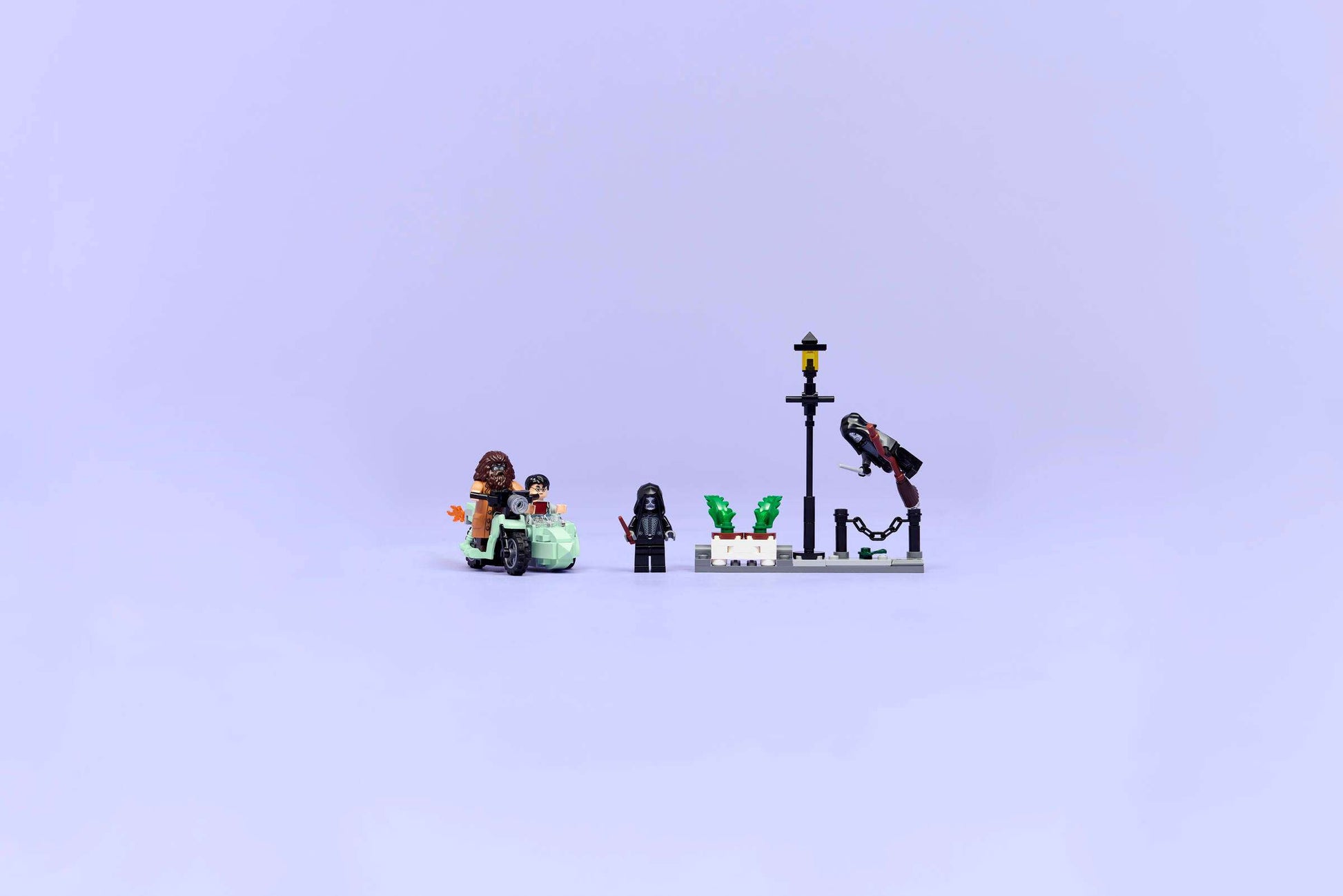 Four LEGO® Harry Potter™ minifigures and accessories, including a streetlamp and plants, are set on a light purple background—perfect for recreating Privet Drive escape scenes with Hagrid’s motorcycle from Legos - Toyhouse.