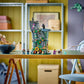 The LEGO® Harry Potter™ Luna Lovegood's House by Legos - Toyhouse is assembled on a desk in a tidy room, with shelves and art supplies in the background, creating a magical scene inspired by Luna’s home.