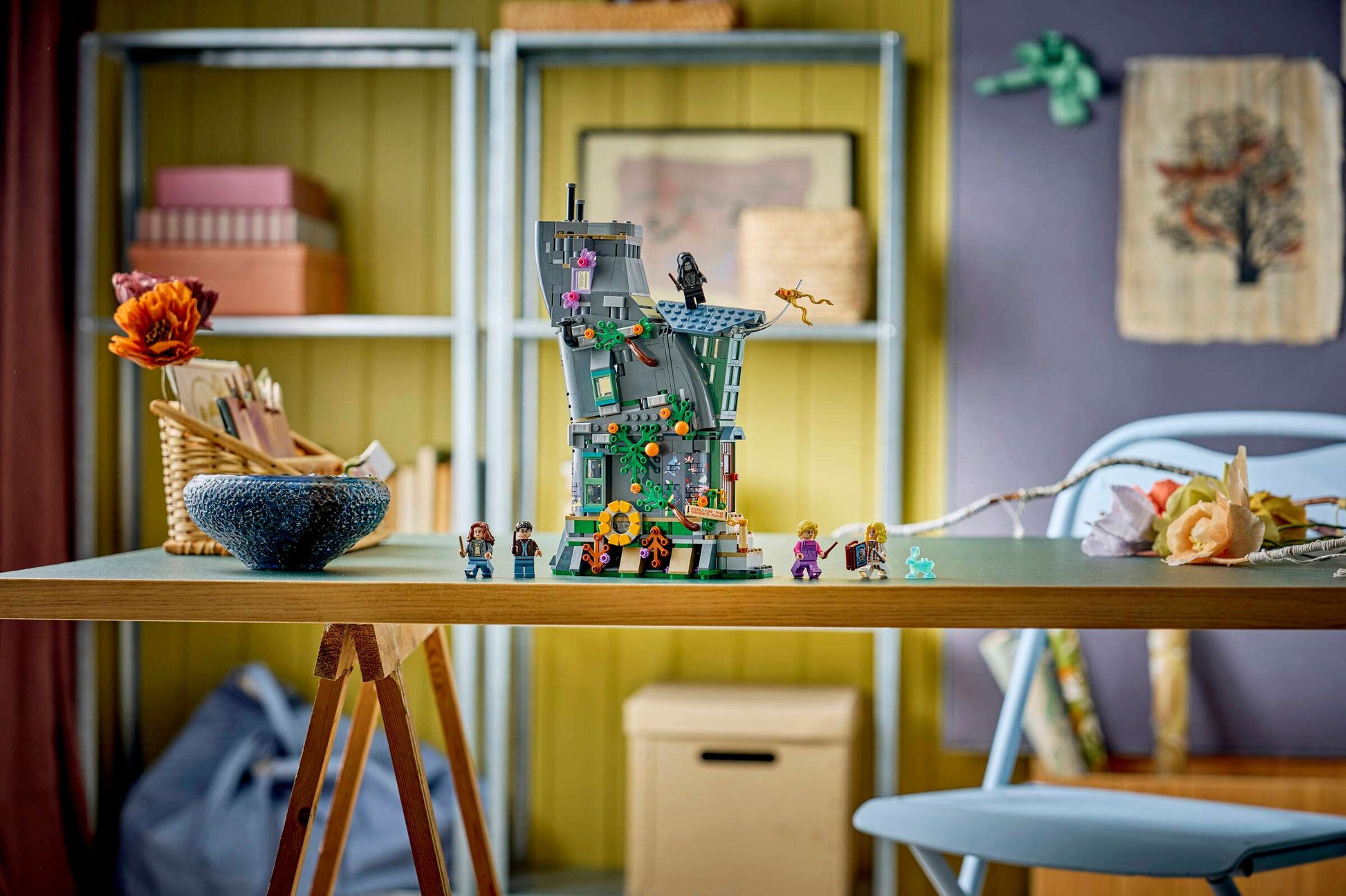 The LEGO® Harry Potter™ Luna Lovegood's House by Legos - Toyhouse is assembled on a desk in a tidy room, with shelves and art supplies in the background, creating a magical scene inspired by Luna’s home.