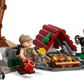 Three minifigures gather at a campsite with gold coins, a red-roofed shelter, mugs, a turkey leg, spider, and accessories—ideal for expanding your Legos - Toyhouse LEGO® Jurassic World™ Raptor & Titanosaurus Tracking Mission set.